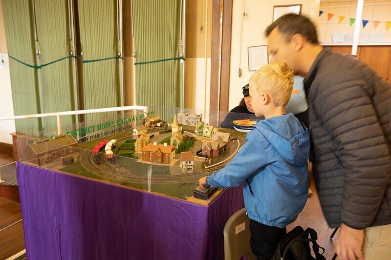 A father and young son leaning in to watch a small layout at the 2019 show