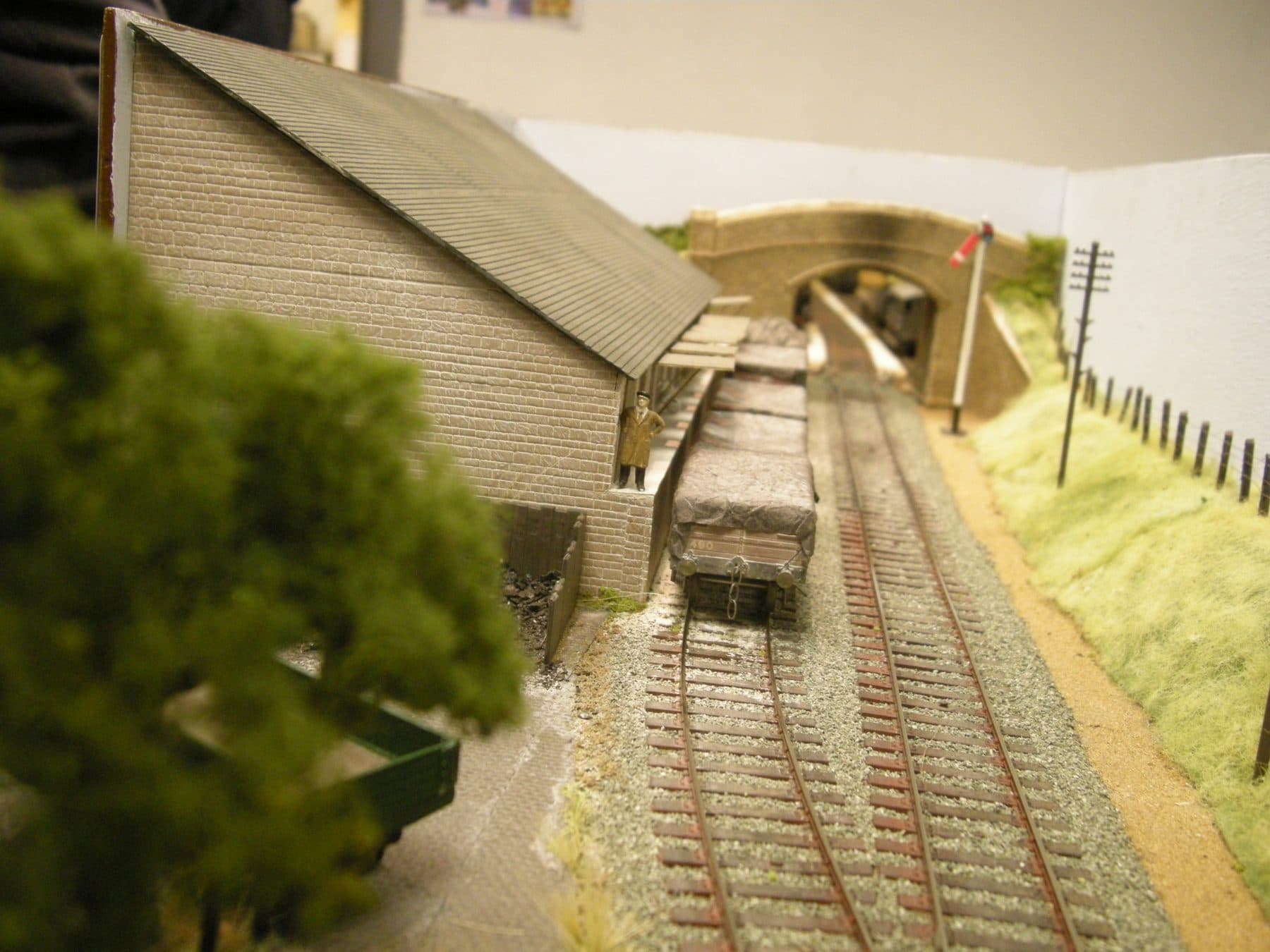 A stone goods shed beside the track at Trewithick, framed by trees